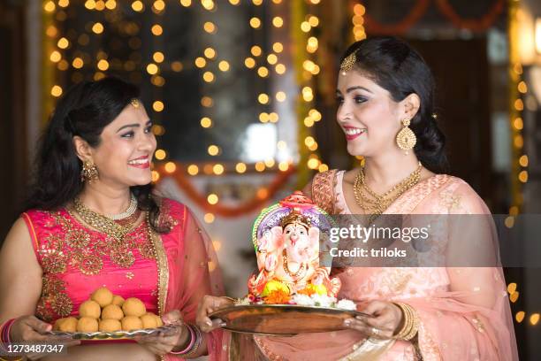 womans carrying statue of hindu god ganesh - ganesh chaturthi stock pictures, royalty-free photos & images