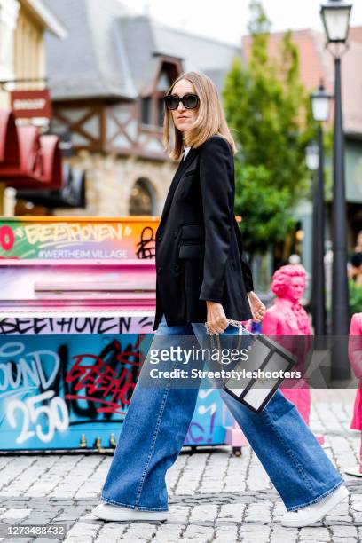 Influencer Annette Weber wearing a dark blue blazer by Escada, a Jeans by Seven of all Mankind, a white T-shirt with print by Michael Kors, a white...