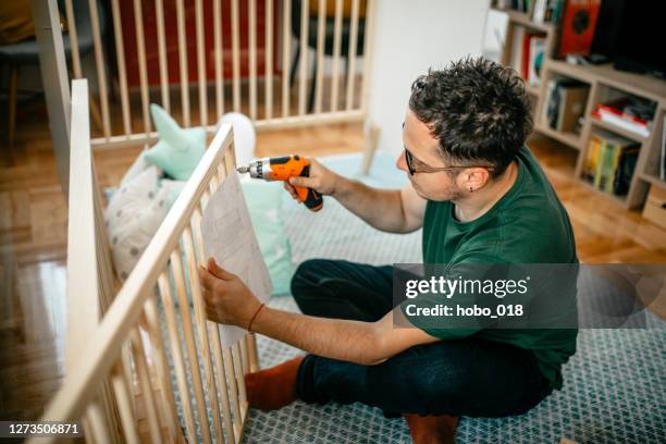 excited future father putting together the baby's crib at home - crib stock pictures, royalty-free photos & images