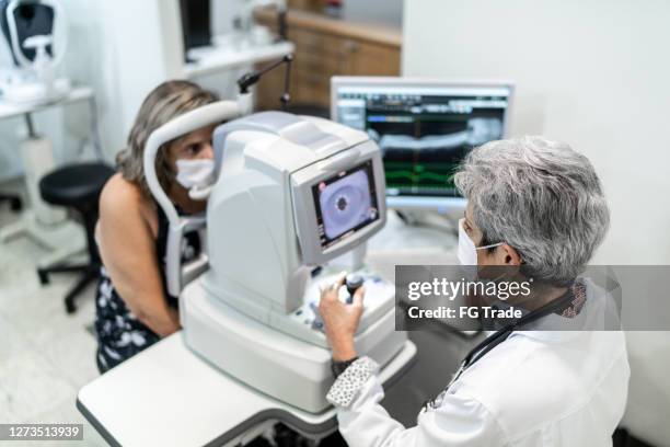 optometrist untersucht patientenaugen - cornea stock-fotos und bilder