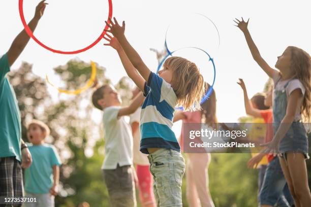 grupp av barn kastar en plast fälgar i parken - ring toss bildbanksfoton och bilder