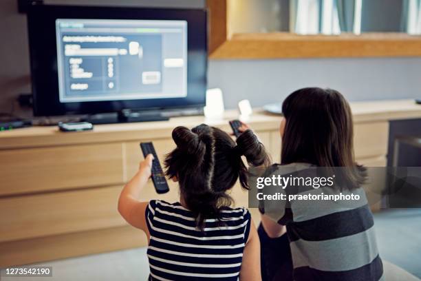 les filles regardent la télévision et utilisent des télécommandes - kids menu photos et images de collection