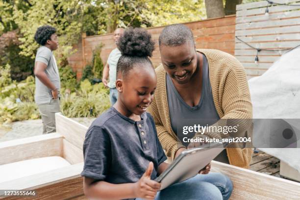 mom and daughter using tablet in a patio - 10-15 2004 stock pictures, royalty-free photos & images