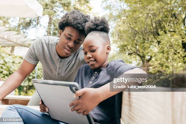 siblings with tablet in the patio - teen sibling stock pictures, royalty-free photos & images