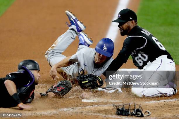 Austin Barnes of the Los Angeles Dodgers scores against catcher Drew Butera and pitcher Mychal Givens of the Colorado Rockies on a wild pitch in the...