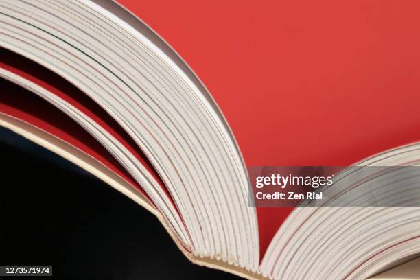 book open to a blank page in red showing binding against black background - literature abstract stock pictures, royalty-free photos & images