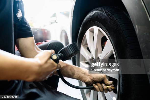 mechanic tire air pressure test in auto repair shop - ventil stock-fotos und bilder