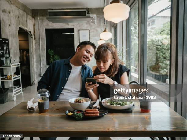 giovani coppie asiatiche che mangiano cibo in un bar. - coppie cibo food bistrot foto e immagini stock