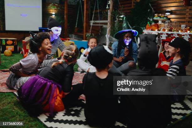 parents telling scary stories to kids at outdoor halloween party - horror story stock pictures, royalty-free photos & images