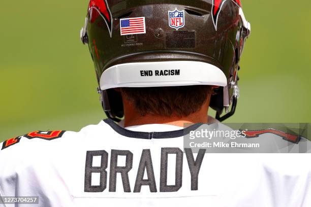 The message "End Racism" is seen on the helmet of Tom Brady of the Tampa Bay Buccaneers as he warms up before the game against the Carolina Panthers...