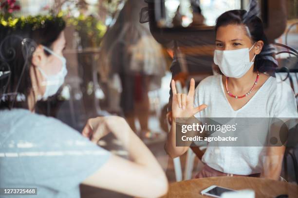 two young woman with mask speak in sign language - american sign language stock pictures, royalty-free photos & images