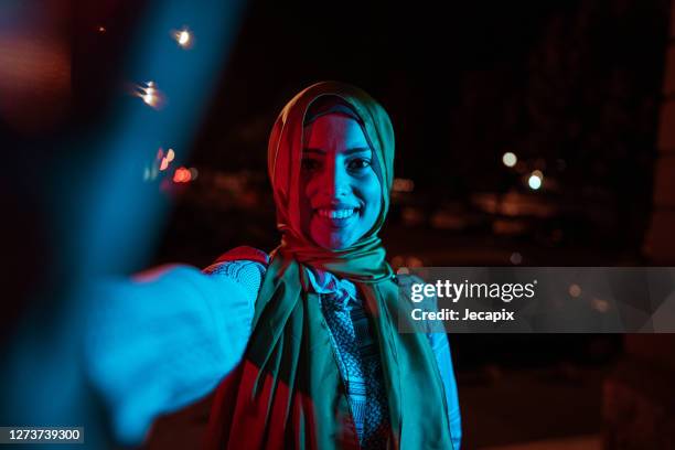 young muslim woman taking selfie outdoors at night - neon lighting smiling stock pictures, royalty-free photos & images