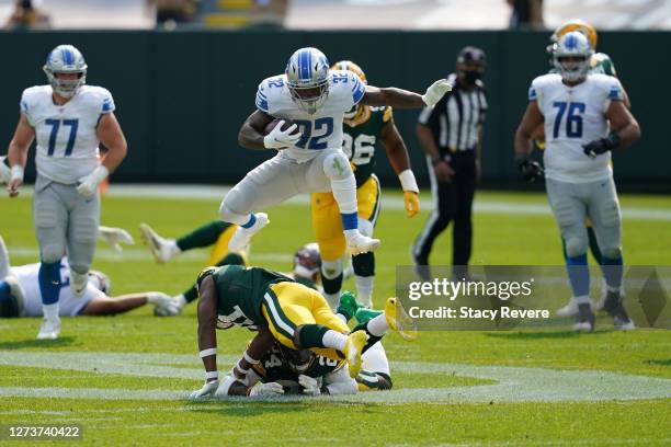 Andre Swift of the Detroit Lions jumps over Adrian Amos of the Green Bay Packers during the second half at Lambeau Field on September 20, 2020 in...