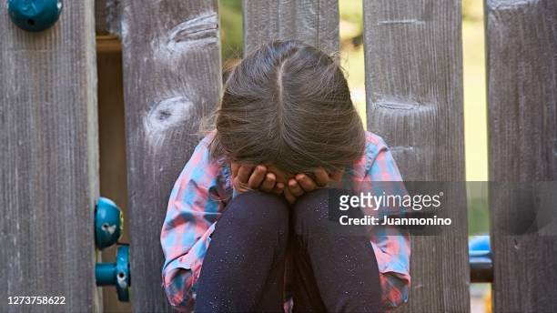 weinendes kind mädchen sitzt auf dem boden und bedeckt sein gesicht - missbrauch stock-fotos und bilder