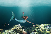 Underwater Mermaid Swimming Among Ocean Coral Reef