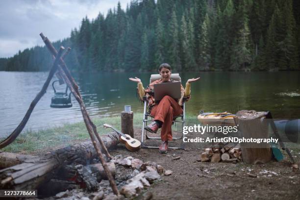 young woman is working on her portable computer during her vacation at the mountains - sitting by fireplace stock pictures, royalty-free photos & images