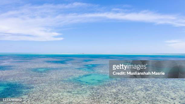 the ocean with corals, blue sky background and clouds. - zonne eiland stockfoto's en -beelden