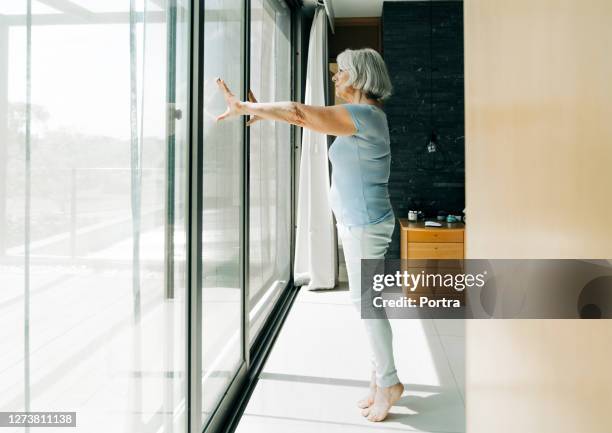 elderly woman standing on tiptoe in bedroom - tiptoe stock pictures, royalty-free photos & images