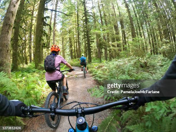 pov, mountain biker following family on single track forest trail - vancouver stock pictures, royalty-free photos & images