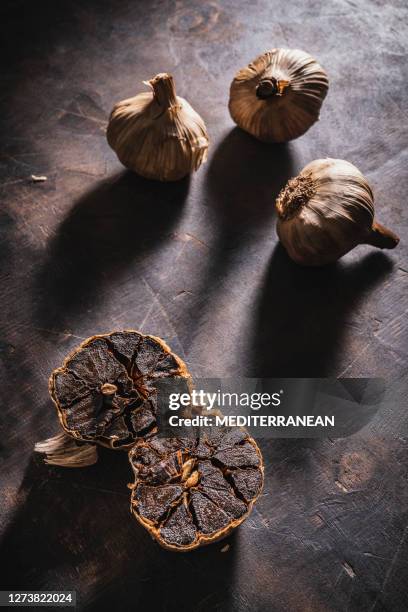 black garlic aged bulbs and cloves on a dark background - alho imagens e fotografias de stock