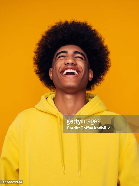 african american man with african hairstyle wearing hoodie standing over isolated yellow background - hooded top stock pictures, royalty-free photos & images