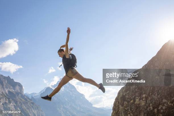 ung kvinna hoppar av bergsrygg vid soluppgången - leap of faith activity bildbanksfoton och bilder