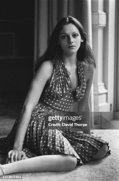 British fashion model Tamasin Day-Lewis, daughter of Anglo-Irish poet Cecil Day-Lewis, kneeling on a carpeted floor wearing a halterneck dress with...