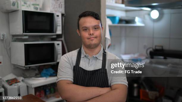 portrait of a chef standing with arms crossed in a commercial kitchen - down syndrome cooking stock pictures, royalty-free photos & images