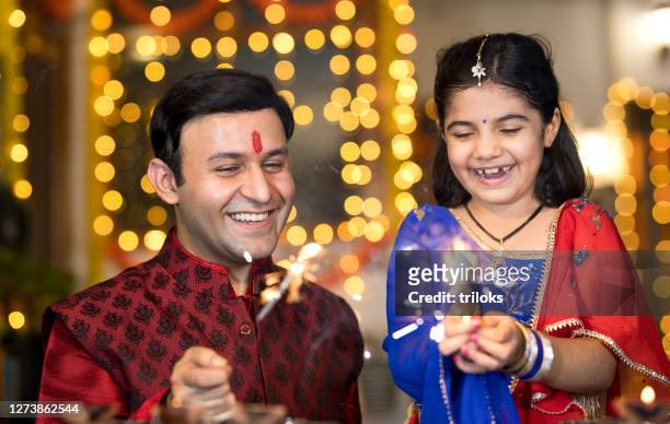 vater und tochter spielen mit crackern während diwali festival - diwali stock-fotos und bilder