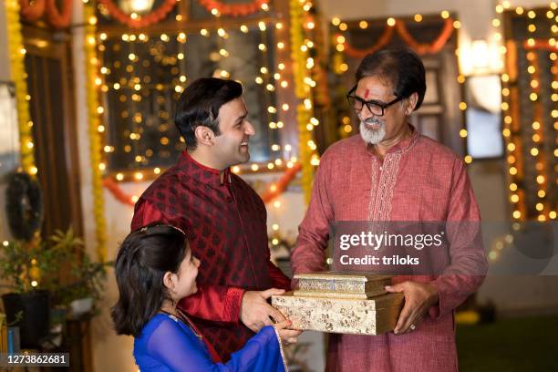 father and daughter presenting festival greeting gift to elderly father and exchanging good wishes - diwali family stock pictures, royalty-free photos & images