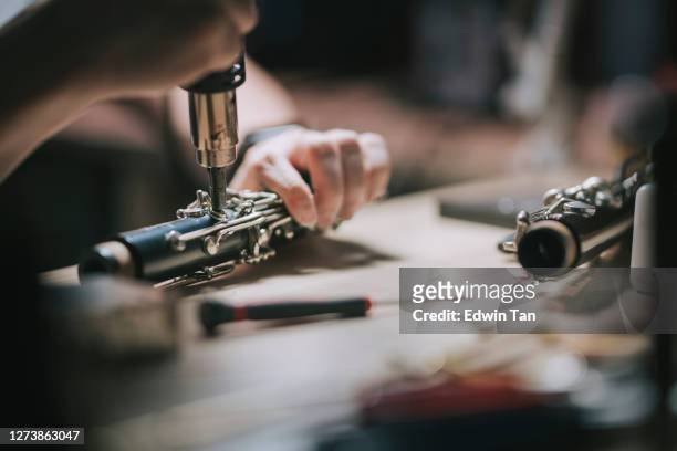 homme chinois asiatique vérifiant et réparant l’instrument de vent de musique de saxophone de soprano dans son atelier - saxophone photos et images de collection