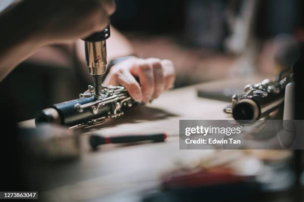 aziatische chinese mens die het controleren en het herstellen van het blaasinstrument van de sopraansoonfoonmuziek in zijn workshop controleert en herstelt - instrumentenmaker stockfoto's en -beelden