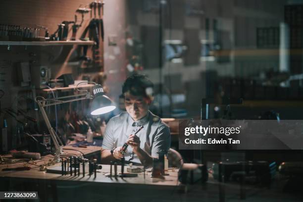 reflection Asian chinese man checking and repairing Soprano saxophone music wind instrument in his workshop