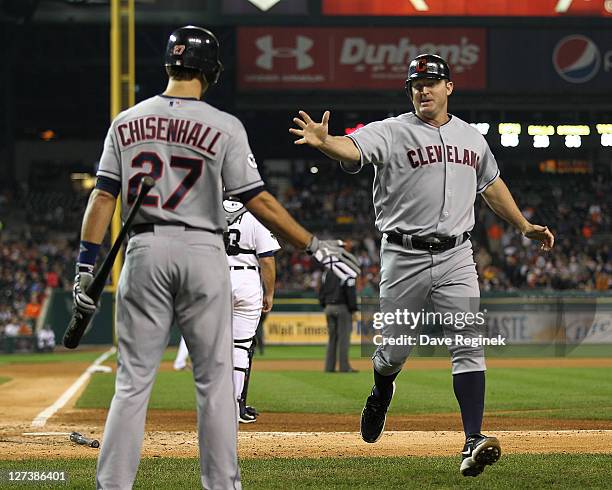 Jim Thome of the Cleveland Indians scores a run and slaps hands with teammate Lonnie Chisenhall against the Detroit Tigers during a MLB game at...