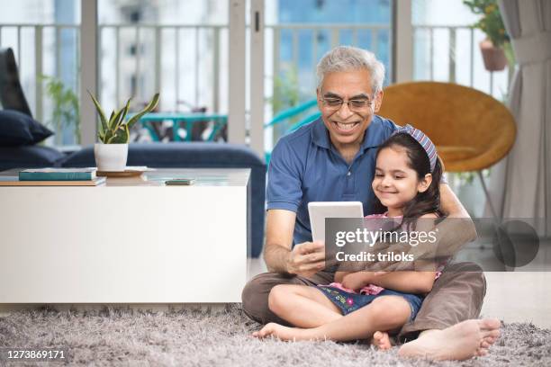 grandfather with granddaughter using digital tablet - indian grandparents stock pictures, royalty-free photos & images