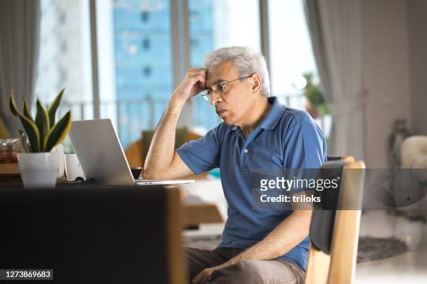 worried senior man using laptop at home - senior men computer stock pictures, royalty-free photos & images