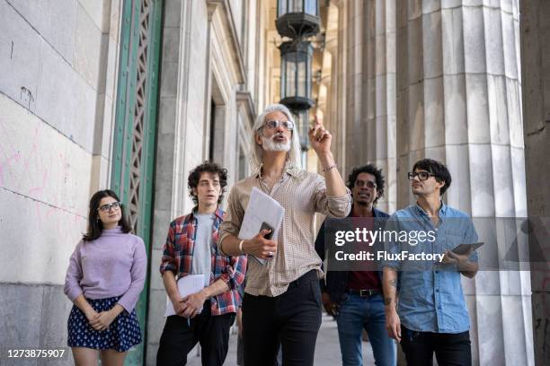 professore anziano che mostra i suoi nuovi studenti in giro per il campus - explain foto e immagini stock