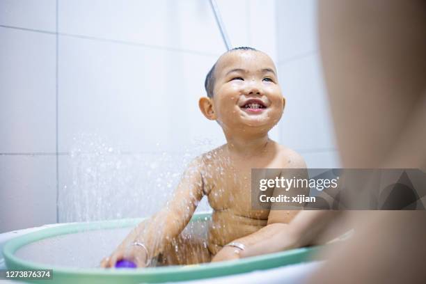 de hulp van de moeder weinig baby die bad neemt - washing tub stockfoto's en -beelden