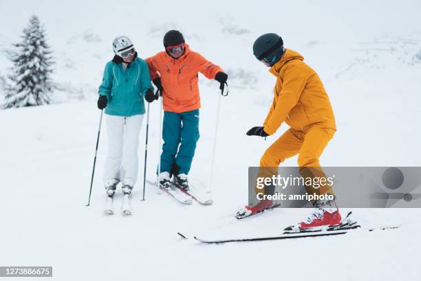ski instructor teaching active senior couple - professional skiers stock pictures, royalty-free photos & images