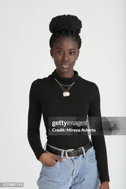 portrait of an african american millennial female with long braids, in a bun, wears a black turtleneck and jeans, in a white studio setting. - polo necks stock pictures, royalty-free photos & images