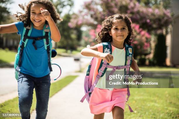 young girls running outside wearing backpacks - organismo vivo imagens e fotografias de stock