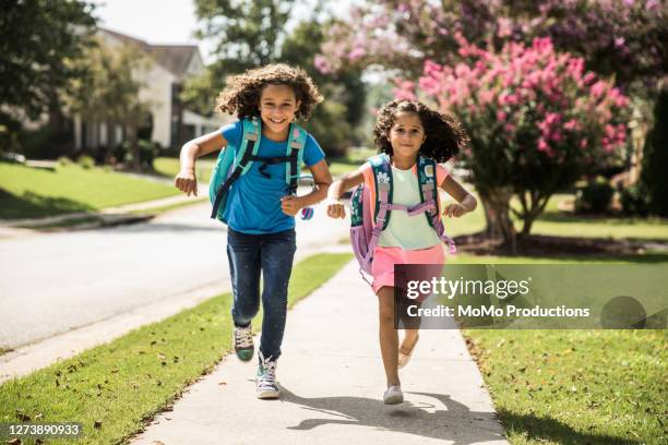 young girls running outside wearing backpacks - enfant cartable photos et images de collection