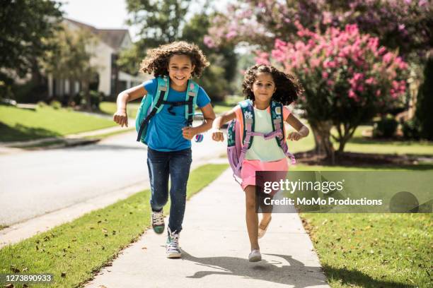 young girls running outside wearing backpacks - green shoes stockfoto's en -beelden