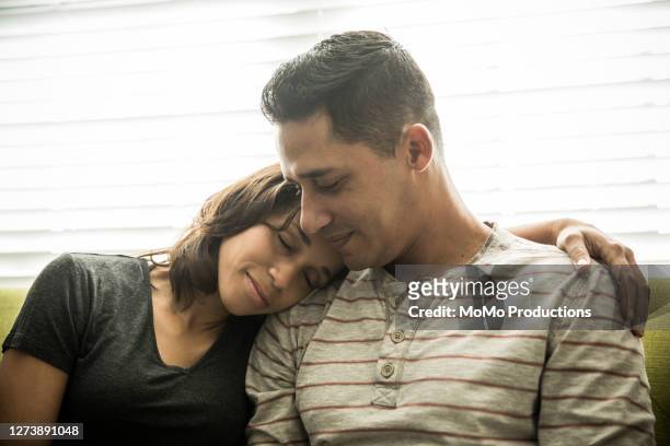 husband and wife snuggling on sofa at home - head on shoulder stock pictures, royalty-free photos & images