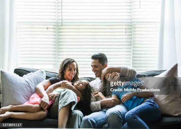 portrait of young family of sofa at home - person gemischter abstammung stock-fotos und bilder
