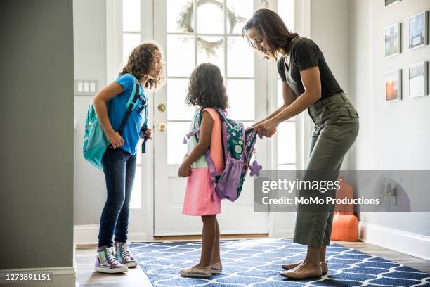 mother packing daughters backpacks for school - schulrucksack stock-fotos und bilder