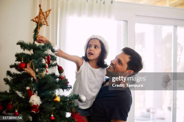 vader en dochter die de kerstboom verfraaien. - christmas summer stockfoto's en -beelden