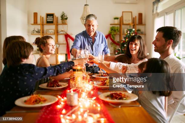 großvater schlägt einen toast beim weihnachtsessen in buenos aires vor - warmes abendessen stock-fotos und bilder
