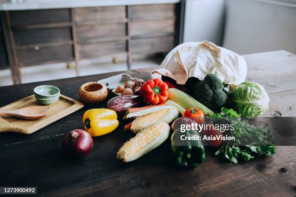 un sac réutilisable rempli de légumes biologiques colorés et frais et d’épicerie s’étendant sur une table rustique en bois. zéro déchet shopping et concept de style de vie durable - cuisine du monde photos et images de collection