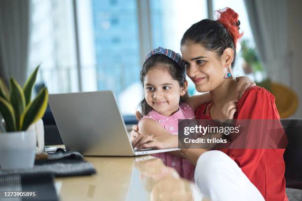 happy little girl embracing her mother while working at home - indian mother and child stock pictures, royalty-free photos & images